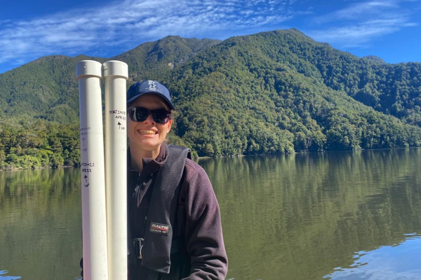 An image of Adelaine Moody, smiling, doing field work on a lake.
