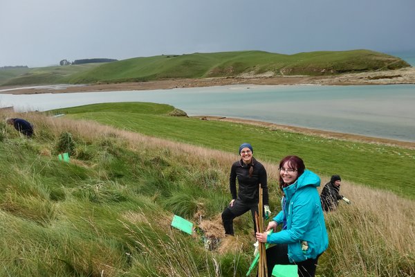 Lucia and two other people standing on a hill doing field work.